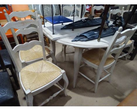 A limed oak effect circular kitchen table with single spare leaf together with a pair of 6 matching ladder back and rush seat