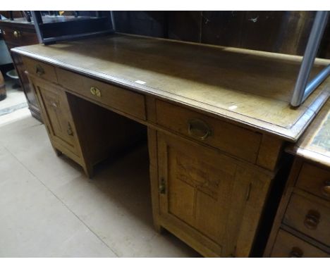 An Art Nouveau oak twin pedestal writing desk with fitted drawers and cupboard pedestals, carved decoration, length 5'3", hei
