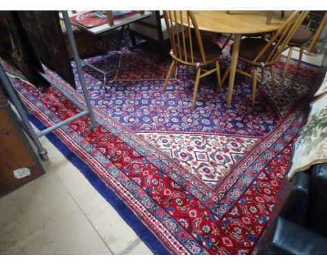 A large blue and red ground Persian design rug with symmetrical pattern and lozenge panel, length 13'4" x 9'4" approx.