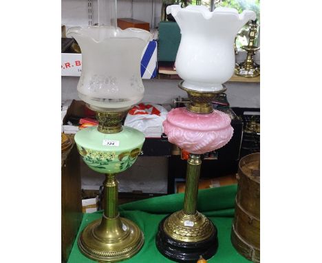A brass oil lamp with painted glass font and another with pink glass font.