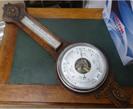 A carved oak cased wall aneroid barometer with thermometer.