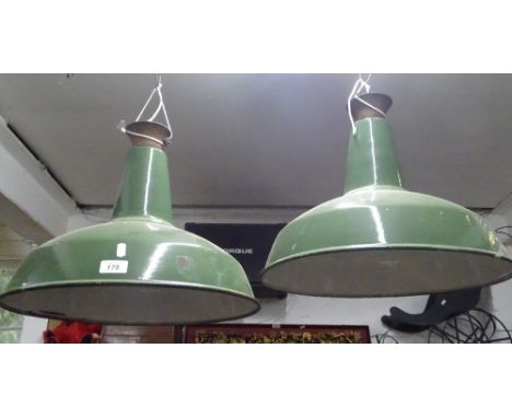 A pair of industrial green and white enamel ceiling light shades.