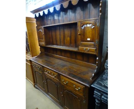 A good reproduction oak dresser, the top having shelves, cupboards and drawers, the base fitted with 3 frieze drawers and fie