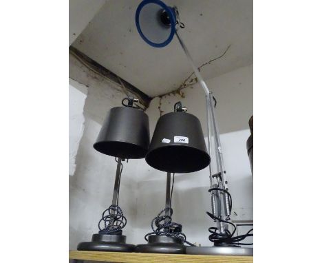 An angle-poise lamp and a pair of adjustable desk lamps with black metal shades.