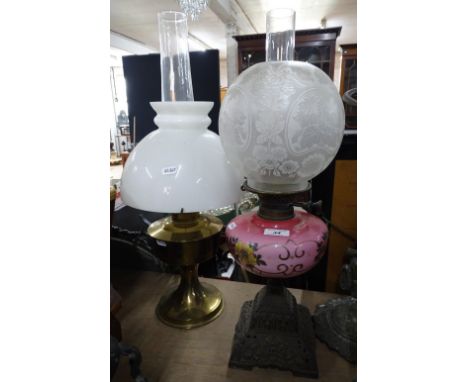 A Victorian pink glass oil lamp on cast-iron base with etched shade, height 22", and another brass oil lamp (2)