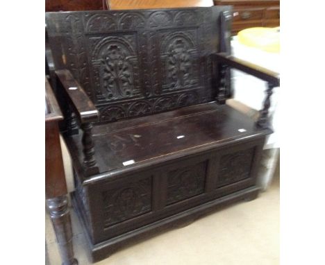 A carved and panelled oak monks bench, W97cm.