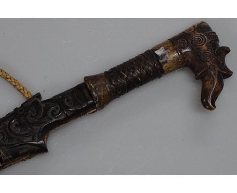 An antique Dayak head hunting swordwith carved horn handle and carved wood scabbard, overall length 24"