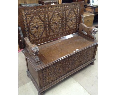 A 1920's oak monks bench, with carved front sitting on bun feet, W 118cm.