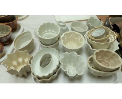 A collection of approximately 15 white ceramic jelly moulds