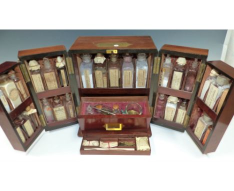 An Apothecary's vinatge travelling medicine mahogany cabinet with twin hinged front sections, fitted with original bottles, s