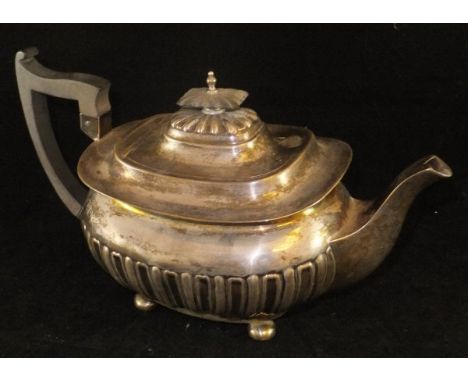 An Edwardian silver teapot of rectangular bellied form with half reeded / fluted decoration, raised on four ball feet, with e