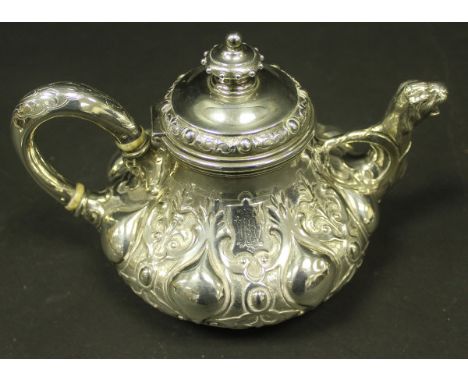 A Victorian silver teapot of bulbous form with profusely embossed decoration, the spout in the form of a beast's head (by Ben