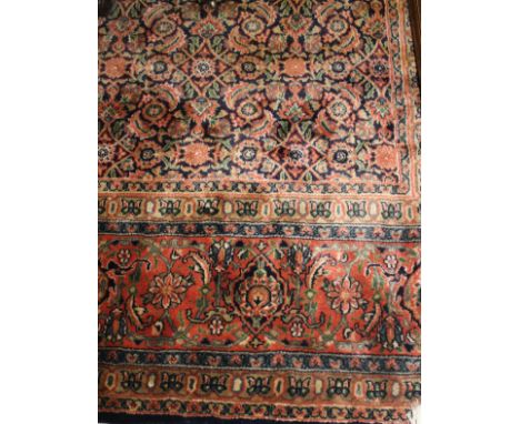 A Persian carpet, the central panel set with all over floral design on a blue ground, within a stepped green, salmon, blue an