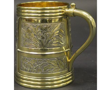 A Victorian silver gilt mug of cylindrical tapering form decorated with floral set panels and ringed top and base, stamped "H