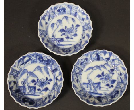 A set of three Kangxi (circa 1700) saucers, each with central garden and mountain decoration within a fan decorated border, t