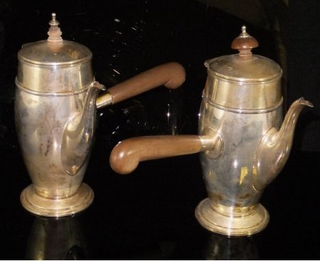 A pair of George V silver cafe au lait pots with turned wooden finial and wooden handle, both raised on circular stepped base