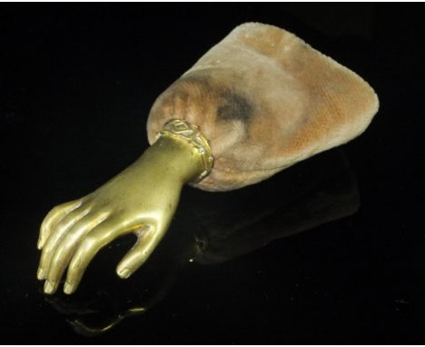 A Victorian brass mounted pin holder, the finial as a ladies hand with bracelet above a brown velvet "cuff" containing folds 