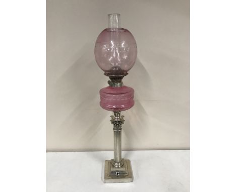 A Victorian Corinthian column oil lamp with pink glass shade 