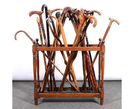 An interesting collection of twenty-six walking sticks, in an old oka stick stand, width 71cm, height 63cm.