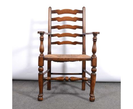 Oak ladder-back elbow chair, wavy rails, rush seat, turned legs, width 62cm.