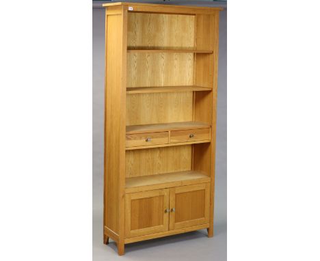 A light oak tall standing open bookcase fitted with an arrangement of shelves, drawers &amp; a cupboard, 96.75cm wide x 199cm