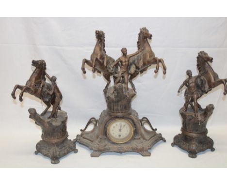A bronzed spelter mantel clock in the form of a gladiator with horses flanked by a pair of accompanying spelter horses and gl