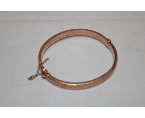 A 9ct gold oval bangle with engraved decoration (8g)
