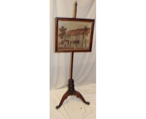 A Victorian mahogany pole screen with tapestry inset panel depicting a cottage scene with figures on tripod base