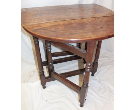 An old oak oval gate leg table on baluster turned supports, 34" x 29"
