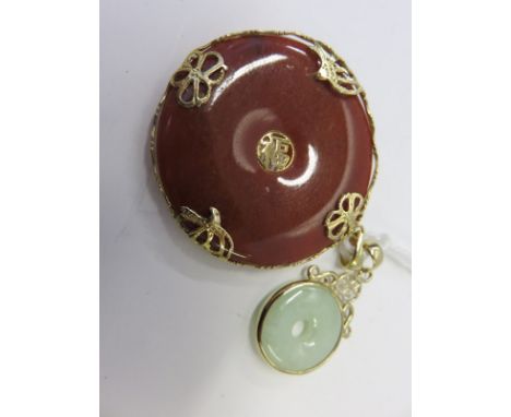 CHINESE JADE PENDANTS, circular red jade Chinese pendant with gold mounts, 3.5cm dia, also a small green jade gold pendant