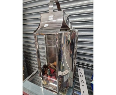 A glazed chrome lantern containing pine cones and decorative gourds