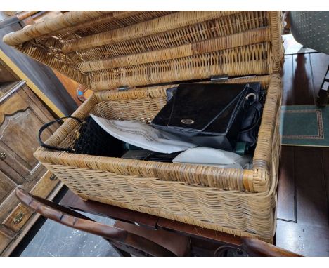 A wicker hamper containing various ladies' handbags.