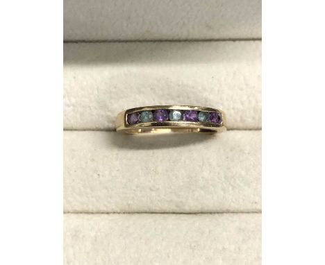 A 9ct hallmarked gold channel set half eternity ring. Set with amethysts and emeralds. Ring size M. Weight 1.8 grams. 