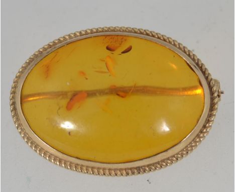 A  vintage 9ct gold hallmarked brooch pin set with a single amber cabouchon in a bezel rope twist setting with roller clasp. 