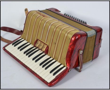 A vintage mid 20th century Hohner Arietta piano accordion, red pearloid finish, with original hard case and some music sheets