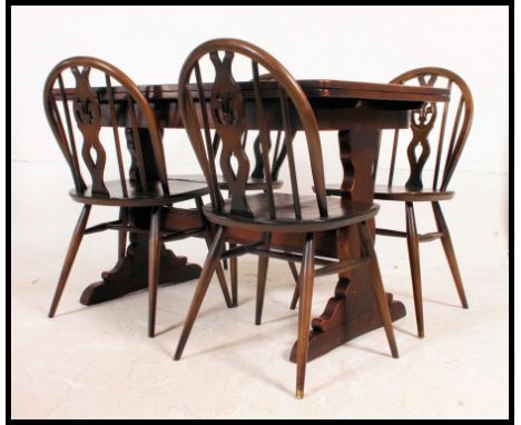 An early Ercol dark wood draw leaf refectory dining table together with a set of Ercol Windsor type dining chairs with saddle