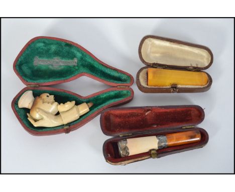 A cased amber cheroot holder along with a silver collared cased cheroot holder with a meerschaum pipe in the form of a hand h