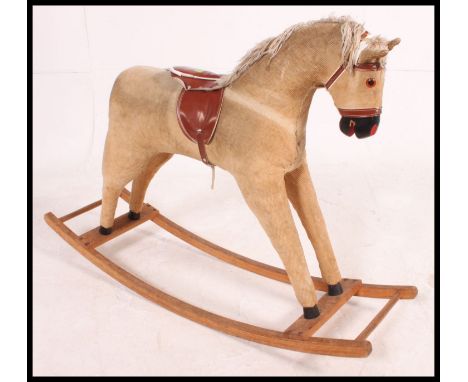 A retro 1970's corduroy rocking horse with saddle and stirrups raised on wooden rockers
