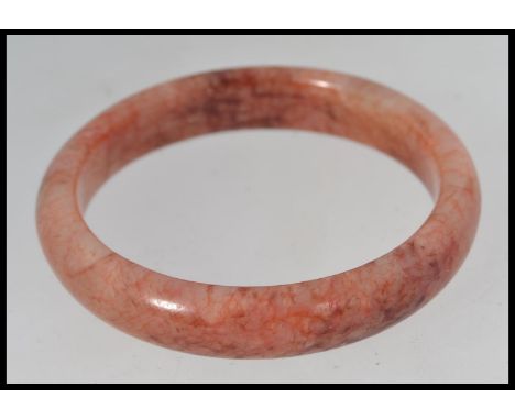 A Chinese 20th century jade bangle, the stone of red hue