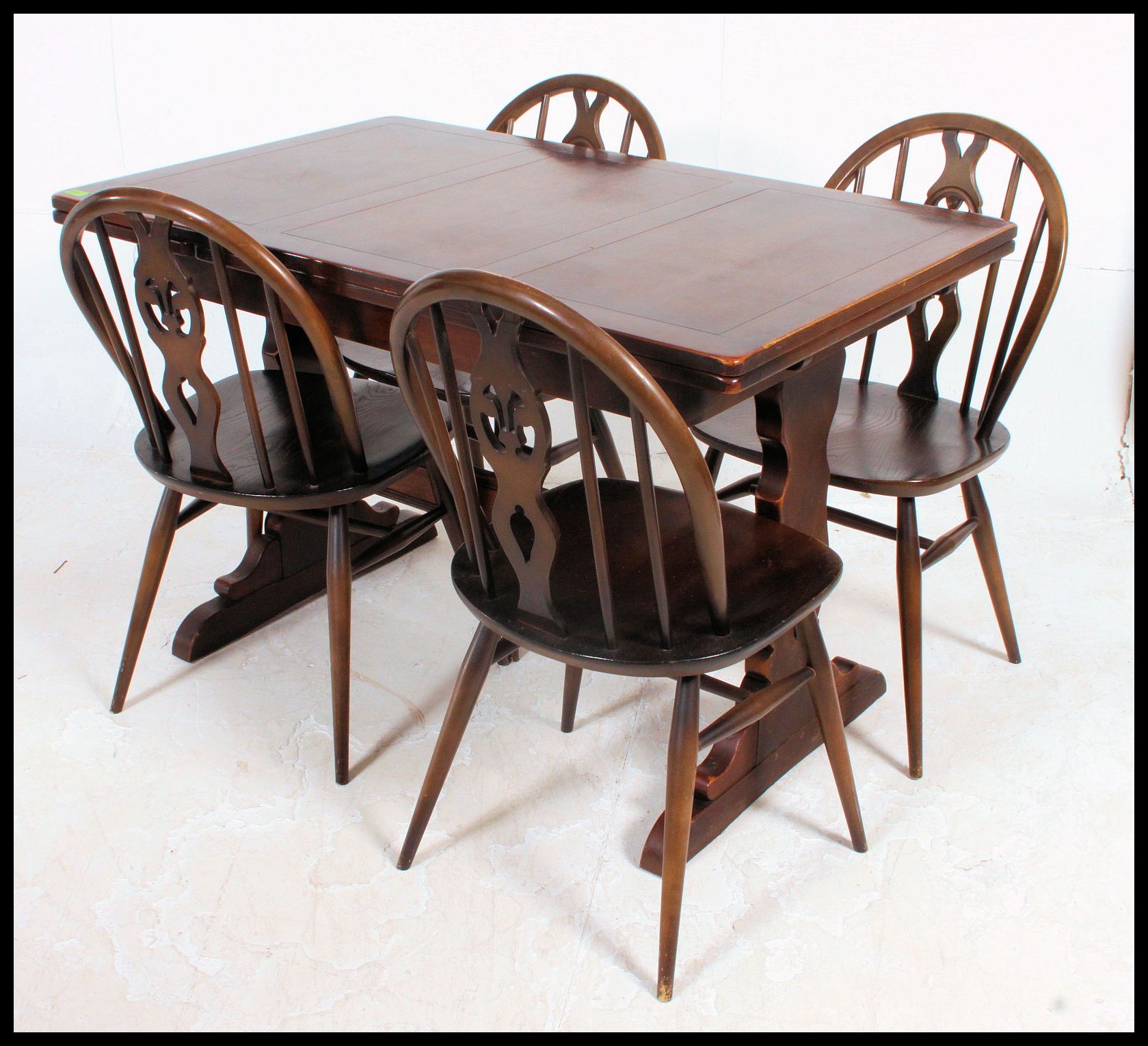 An early Ercol dark wood draw leaf refectory dining table together with a set of Ercol Windsor ty