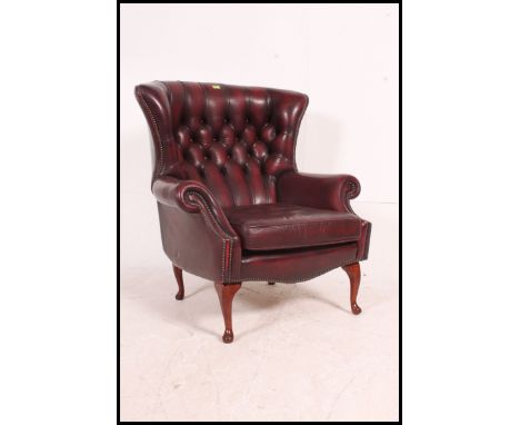 A stunning red leather oxblood Chesterfield wingback armchair raised on cabriole legs with button back leather upholstery.