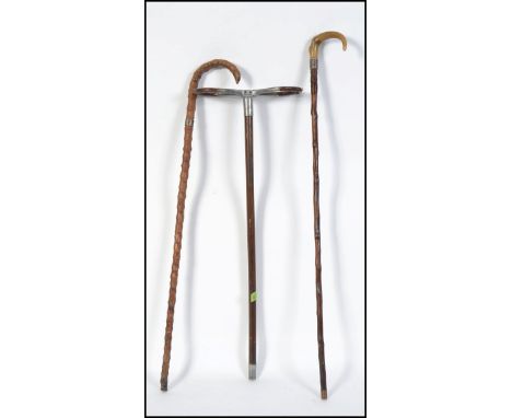 A 20th century shooting stick along with two silver collared walking sticks both having tapering stems with crook handles