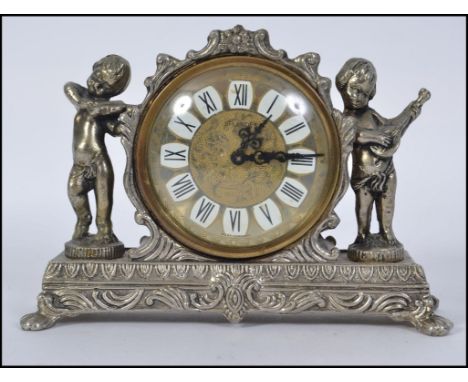 A Small 20th century mantel clock set in a white metal case .  The decorative face with roman numeral chapter ring  being fla