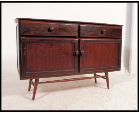 A retro 1970's Ercol style sideboard raised on an unusual clip on turned leg base. The sideboard comprising a series of cupbo