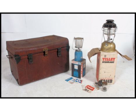 A vintage tin trunk with hinged lid, along with a vintage boxed Tilley lamp and a retro boxed Campingaz lamp. H46xW70xD44cm