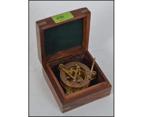 A small nautical sun dial and compass in brass, in brass inlaid hardwood hinged box.  Anchor motif and marked ' Nauticalia Lo
