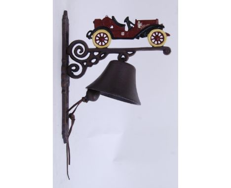 A cast iron exterior hanging door bell on a bracket, the top decorated with a car Hand painted, with bell beneath.