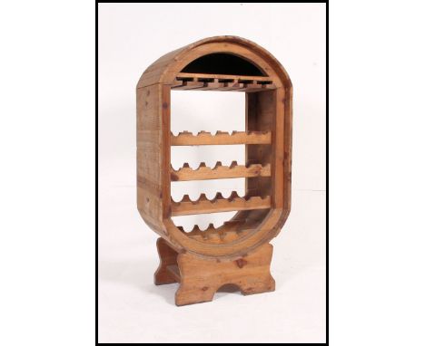 A large rustic pine wine rack of unusual shape having shelf to the top with wine rack centre, all raised on shaped plinth bas