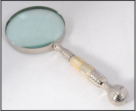 A large good quality silver plated and mother of pearl inset magnifying glass having finial end to handle and large circular 