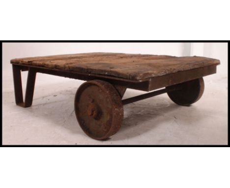 A vintage industrial early 20th century Bogie trolley, having cast iron wheels, iron angular supports, wooden top, ideal for 